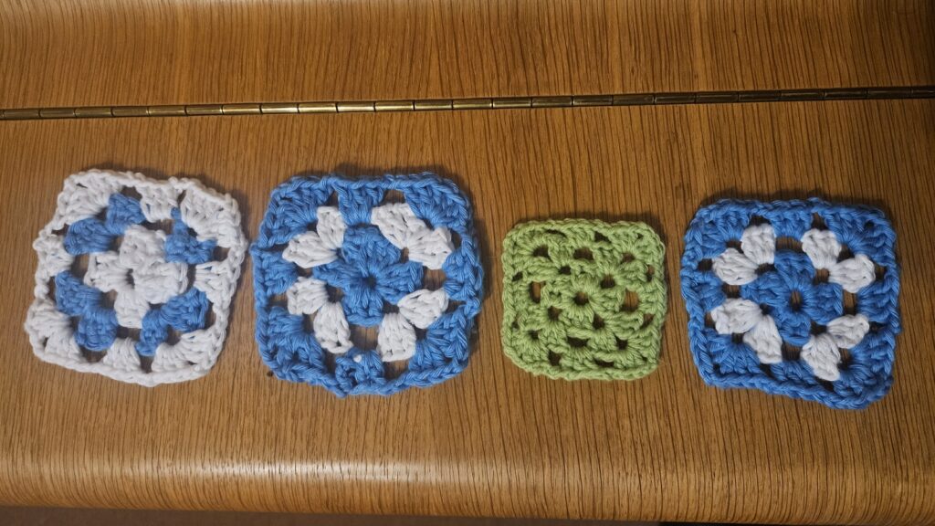 three crotchet blue and white granny squares and 1 green granny square